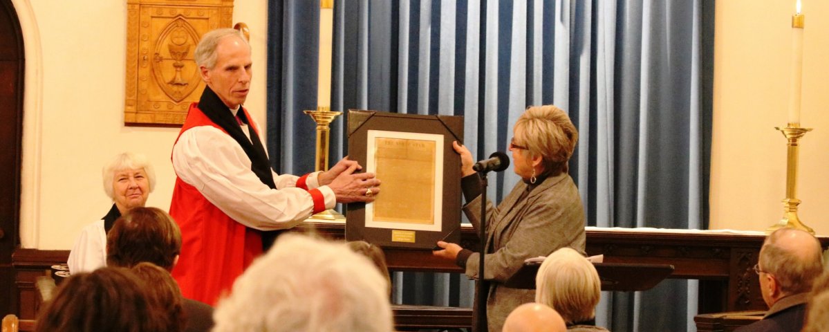 Bishop Doug Fisher hands the award to Lynn Page, deputy general manager at WGBY.