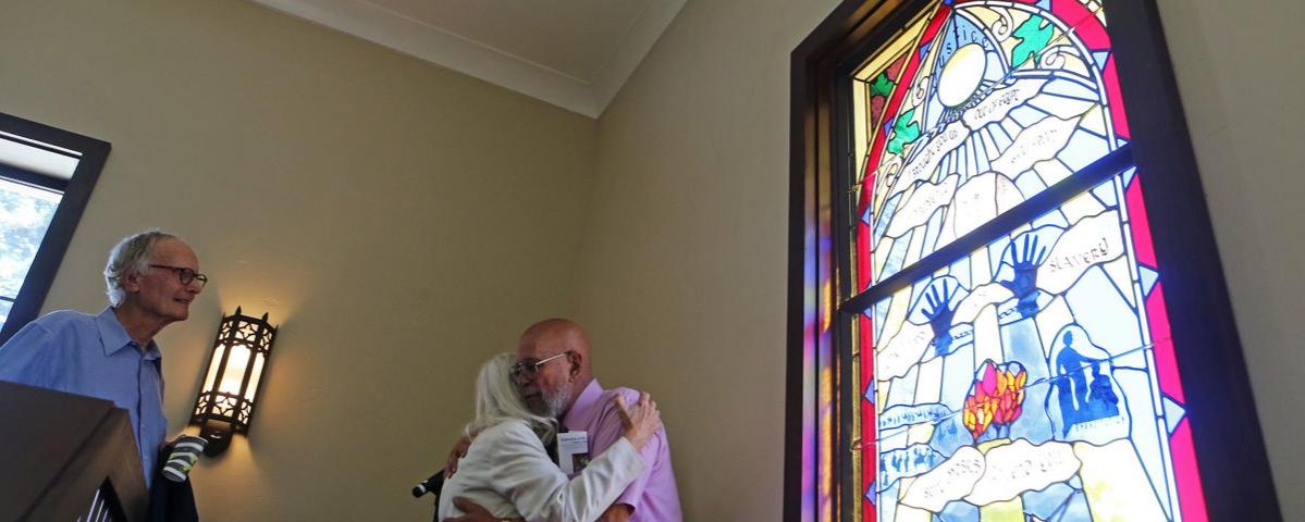 Whitney J. LeBlanc embraces a fellow member of Grace, St. Helena, shortly after the dedication of "Justice," the newest of stained glass windows he has crafted for the church since moving to Napa Valley in 1996.