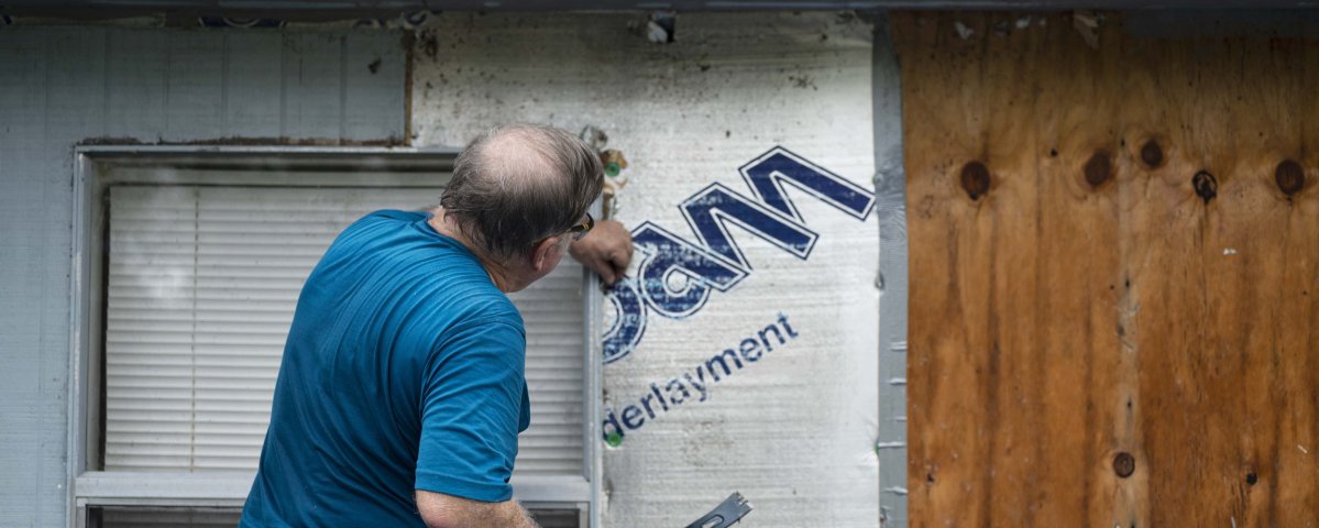 A volunteer installs siding