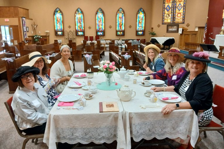 ladies in hats dressed up around a fancy tea setting