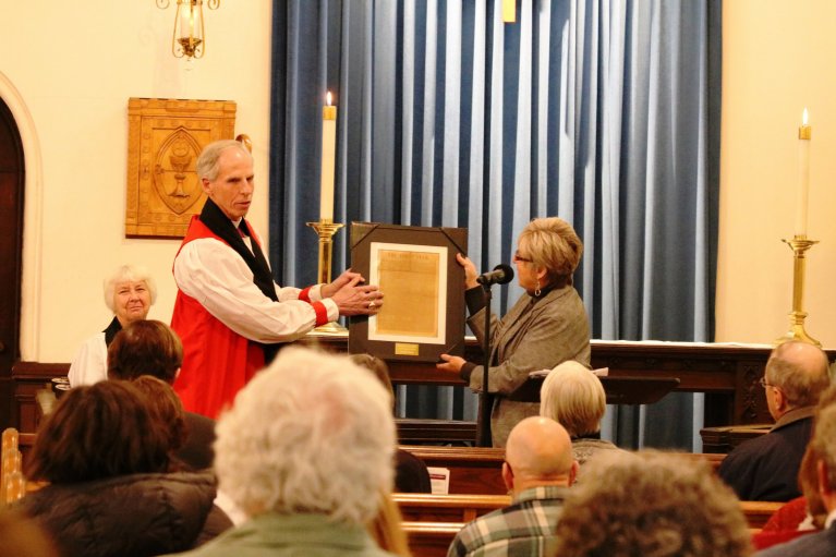 Bishop Doug Fisher hands the award to Lynn Page, deputy general manager at WGBY.